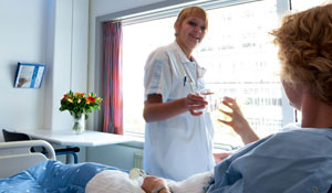 Μια νοσηλεύτρια προσφέρει ένα ποτήρι νερού σε έναν ασθενή