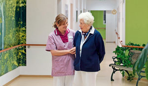 Μια νοσηλεύτρια που φροντίζει μια ηλικιωμένη κυρία σε ένα φωτισμένο διάδρομο