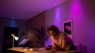 Τα έξυπνα φώτα LED της Philips Hue δημιουργούν ζωντανή μωβ και ροζ ατμόσφαιρα στο σαλόνι, επιδεικνύοντας προσαρμόσιμο ατμοσφαιρικό φωτισμό για βραδιές ταινιών και χαλάρωση σε μοντέρνα σπίτια.