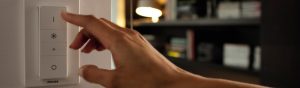 "Έξυπνος ρυθμιστής έντασης LED Philips, ελέγχοντας τον φωτισμό του περιβάλλοντος σε ένα άνετο σαλόνι με ράφια."